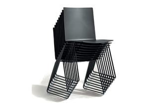 Gestapelde zwarte stoelen met kunststof zitting en metalen buisframe, schuin gerangschikt tegen witte achtergrond.