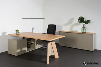 Moderne kantoorwerkplek met houten tafel op houten poten, grijze kasten, zwarte bureaustoel, potplanten en groen blad in glaz