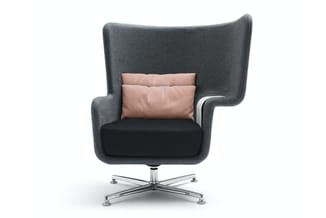Grijze fauteuil met hoge rug en armsteunen, zwart zitgedeelte, roze kussen, chromen kruisvoetsteun op wit oppervlak.