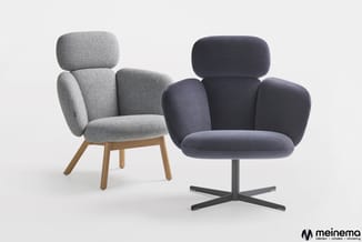 Twee moderne fauteuils: links grijze stof op houten poten, rechts donkerblauwe stof op zwart kruisvoetstessel.