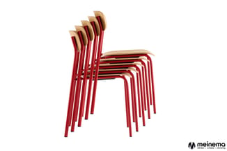 Gestapelde stapelstoelen met rood metalen frame en lichtbeige houten zitting en rug, tegen witte achtergrond.