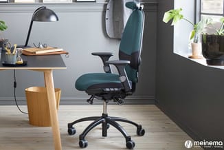 Moderne kantoorwerkplek met groen-zwarte ergonomische bureaustoel, houten bureau, zwarte bureaulamp, planten op vensterbank e