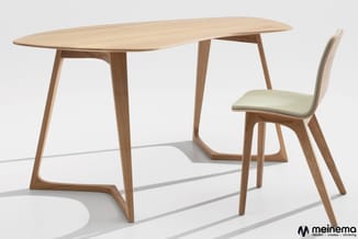 Houten vergadertafel met afgeronde blad en houten stoel met groene zitting op wit vlak.