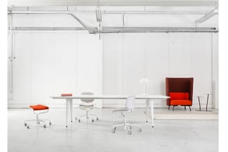 Moderne kantoorruimte met witte tafels, grijze en rode bureaustoel met wielen, rode fauteuil, hanglamp en minimalistische inr