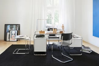 Minimalistische kantoorruimte met buisframe bureau, zwarte stoel, wit kastje en zwart tapijt. Grote raam met witte gordijnen,