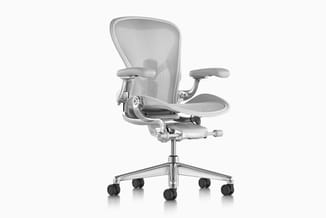 Grijze ergonomische bureaustoel met gazen rugleuning, verstelbare armleuningen, zituitschuiving en wielbasis op witte achterg