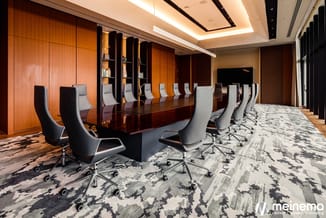 Moderne vergaderruimte met lange donkere tafel, zwarte en grijze bureaustoelen, oranje houten wandpanelen, plafondverlichting