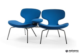 Twee blauwe designstoelen met ergonomische vorm en metalen poten, gepositioneerd rond een klein rond tafeltje in het midden.