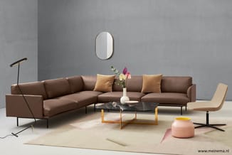 Bruine hoekbank met gouden kussens, zwarte marmeren salontafel met houten onderstel, beige fauteuil, staanlamp, roze poef en