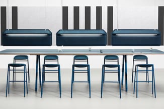 Kantoorruimte met blauwe barstoel-collectie aan lange tafel en drie blauwe soft seating banken tegen muur met zwarte akoestis