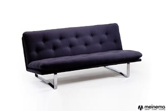 Zwarte slaapbank met gestoffeerde rugkussens, knopen en chromen poten tegen witte achtergrond.