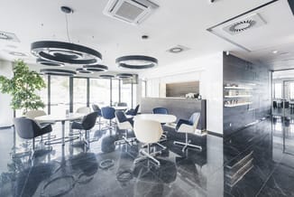 Modern kantoor met ronde zwarte hangende verlichting, zwart-witte bureaustoel, glazen vergadertafel, grijze receptiebalie en
