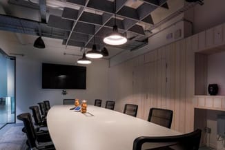 Moderne vergaderkamer met ovale witte vergadertafel, zwarte mesh-stoelen, hangende LED-pendellampen, lichte houten wandpanele