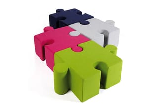Puzzle vormige modulaire zitblokken in groen, roze, grijs en donkerblauw met ineinander grijpende vormen.