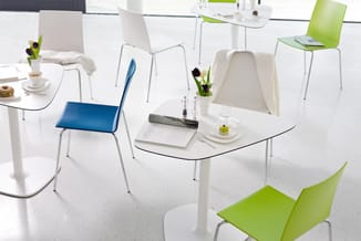Modern kantoor met witte gebogen vergadertafel, stoelen in wit, blauw en groen, bureauaccessoires en bloemen.
