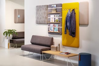 Kantoorruimte met grijze loungebank, houten tafel, gele wandpaneel met haken, grijze wandplaat met houten planken, beige wand