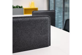 Grijze akoestische schermen op wit bureau in modern kantoor met gele kastenwand op achtergrond.