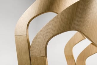 Detail van de gebogen houten rugleuningen van gestapelde Crassevig Mixis stoelen, liggend beeld zonder witte zijstroken.