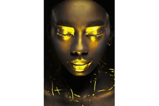 Portretfoto met gele neonverlichting op gezicht en schouders tegen donkere achtergrond.