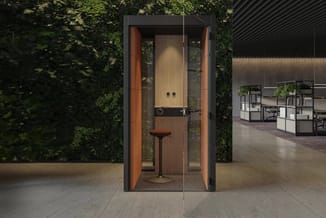 Akoestische belcel met houten binnenwanden en oranje zijpanelen, zwarte stalen frame, ingebouwde zit en werkoppervlak, in ope