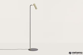 Staande leeslamp met zwart metalen staander, ronde zwarte voetplaat en geborsteld messing lampenkop tegen neutrale achtergron