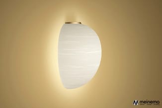 Wandlamp met wit gestructureerd glas en messing montage tegen gele achtergrond.