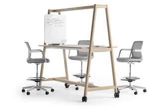 Houten vergadertafel met whiteboard, drie grijze bureaustoelen met wielen en voetsteun, kantoorruimte-opstelling.