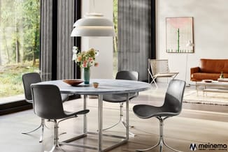 Ronde eettafel met grijze natuurstenen blad en metalen onderstel, omgeven door zwarte stoelen met chromen poten in modern int