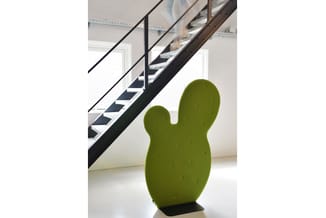 Groene cactus-vormige decoratie in moderne kantoorruimte met zwart-witte trap op achtergrond.