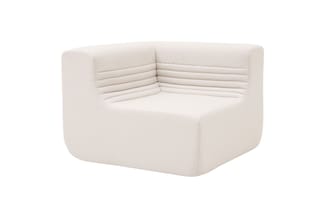 Hoekzitbank in beige stof met gegroefd rugleuning en afgeronde vormen, geïsoleerd tegen witte achtergrond.