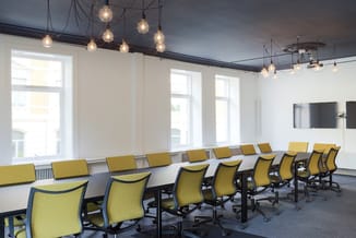 Moderne vergaderzaal met lange witte tafel, gele ergonomische bureaukstoelen, hangende glasverlichting en donker plafond met