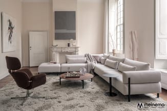 Moderne woonkamer met beige modulaire hoekbank, bruin ribfluwelen fauteuil, ronde houten salontafel op zwart onderstel en gri