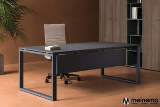 Moderne zwart bureau met grijze frame en zwart onderstel in kantoor met beige stoel, houten kast en plant.