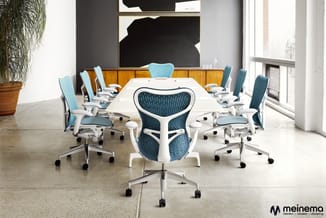 Vergaderruimte met witte vergadertafel, blauwe en witte ergonomische bureaustoelen op wielen, houten buffetkast, zwart kunstw