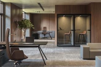 Modern kantoor met houten wanden, zwarte bureau's met bruine stoelen, glazen telefoonboxen met oranje stoelen, beige loungeba