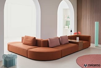 Modulaire hoekbank in terracottakleur met binnenzijde kastcombinatie, decoratieve kussens, in minimalistische woonruimte met