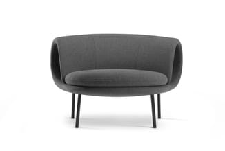 Grijze ronde fauteuil met gewatteerde zitting, gebogen rugleuning en zwarte metalen poten.