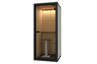 Compacte akoestische belcel met zwart metalen frame, beige/taupe binnenwanden, glazen deur, LED-verlichting en centrale tafel