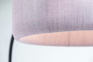 Close-up van de lichtroze stoffen kap van de BuzziJet vloerlamp, met zichtbare weefstructuur, stiknaad en warm verlichte onderzijde.