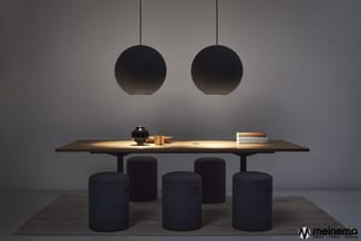 Moderne vergadertafel met donkerbruin blad en zwarte poten, omgeven door vijf donkerblauwe ronde poefs. Twee zwarte hangende