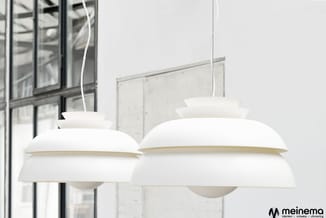Twee witte hangende design-lampen met geschakelde schalen boven elkaar, in minimalistisch interieur met ramen op achtergrond.