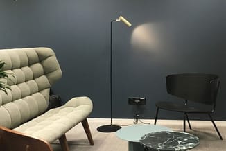 Loungehoek met beige gestoffeerde fauteuil, zwarte metalen staanlamp met gouden kap, lichtblauwe en zwarte marmeren bijzettaf