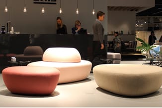 Moderne zitpoefs in rood, wit en beige in een contemporary kantoorinrichting met zwarte receptie en hangende verlichting.