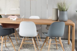 Houten vergadertafel met witte en grijze stoelen met houten poten, grijze rug, potplanten, grijze wandpanelen.