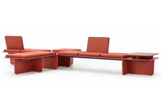 Modulair zitlandschap in terracotta-rood met kussens, hoekbanken en bijzettafels in een open opstelling.