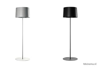 Twee vloerlampen met cilindervormige lampenkap, één in zilvergrijs en één in zwart, elk op rond voetje.