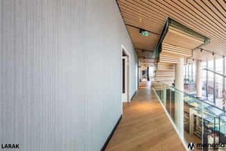 Moderne kantoorgang met houten vloer, witte wand links, glazen afscheiding rechts, houten plafond met stroken, exit-bord zich