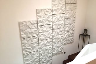 Witte 3D wandpanelen in rechthoekige opstelling op slaapkamermuur naast nachtkastje.