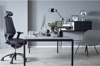 Modern kantoor met zwarte werktafel, ergonomische bureaustoel, grijze bezoekersstoel, zwarte wandkast, bureaulamp en plantend