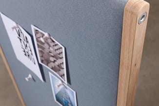 Houten paneel met grijs geluidsabsorberend stof en twee ingelijste zwart-witte foto's eraan bevestigd.